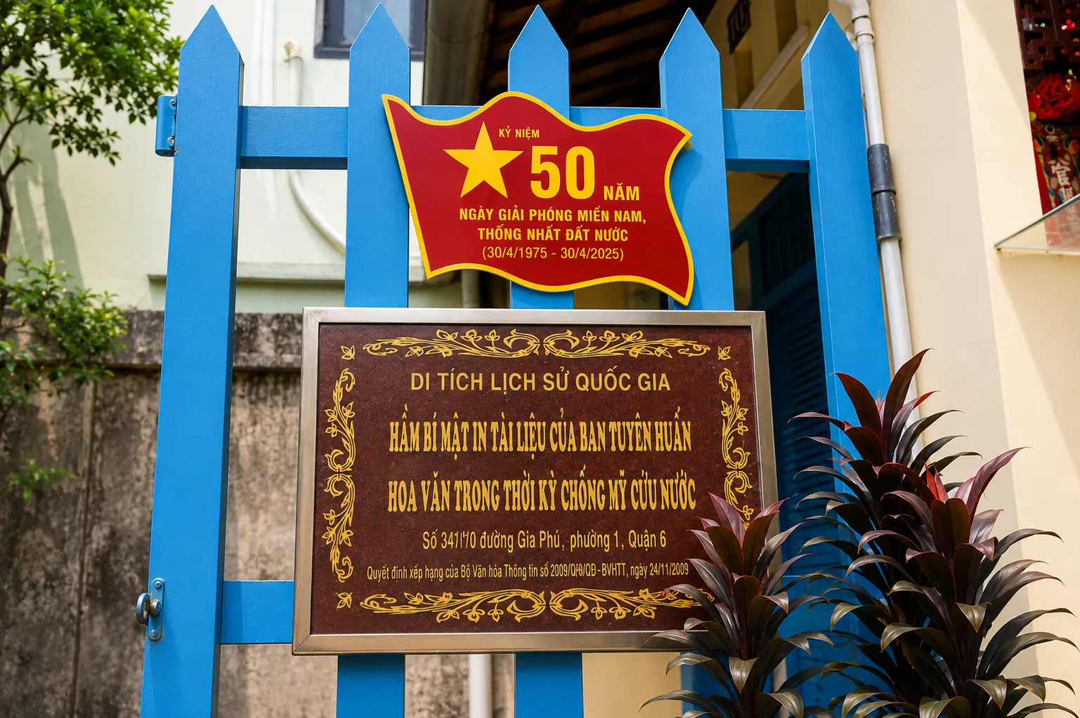 Mặt tiền căn nhà di tích với cửa và cổng màu xanh.