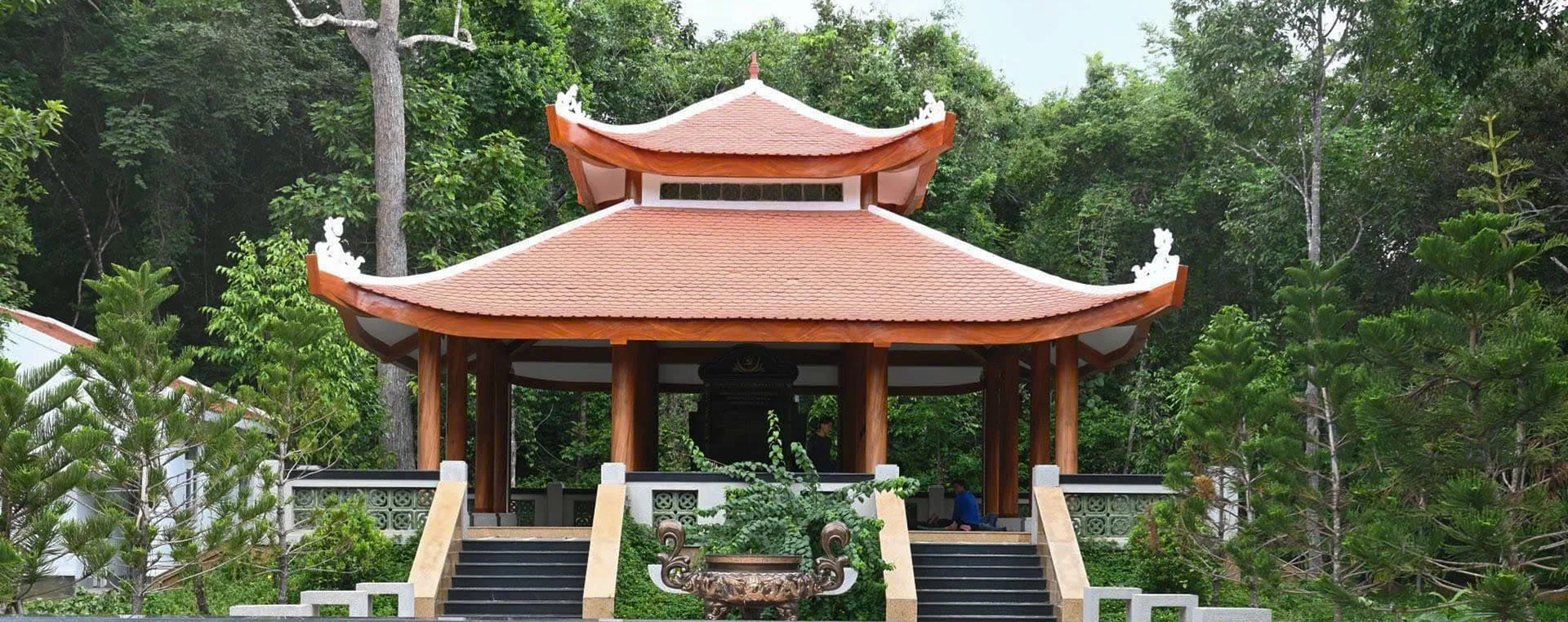 Mặt trước khu nhà tưởng niệm Căn cứ Ban Hoa vận Trung ương Cục miền Nam giữa không gian cây xanh.