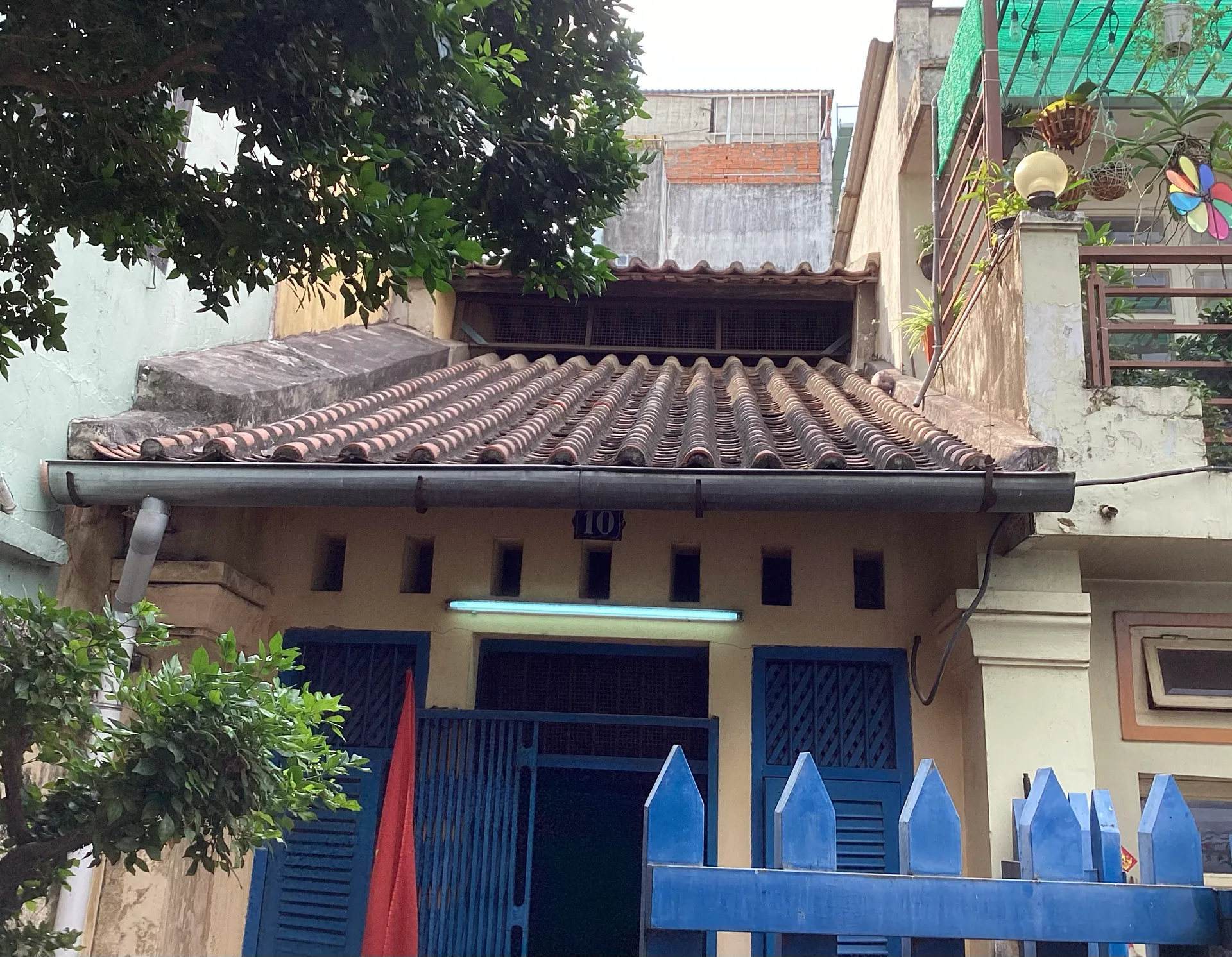 Mặt tiền căn nhà di tích với cửa và cổng màu xanh.