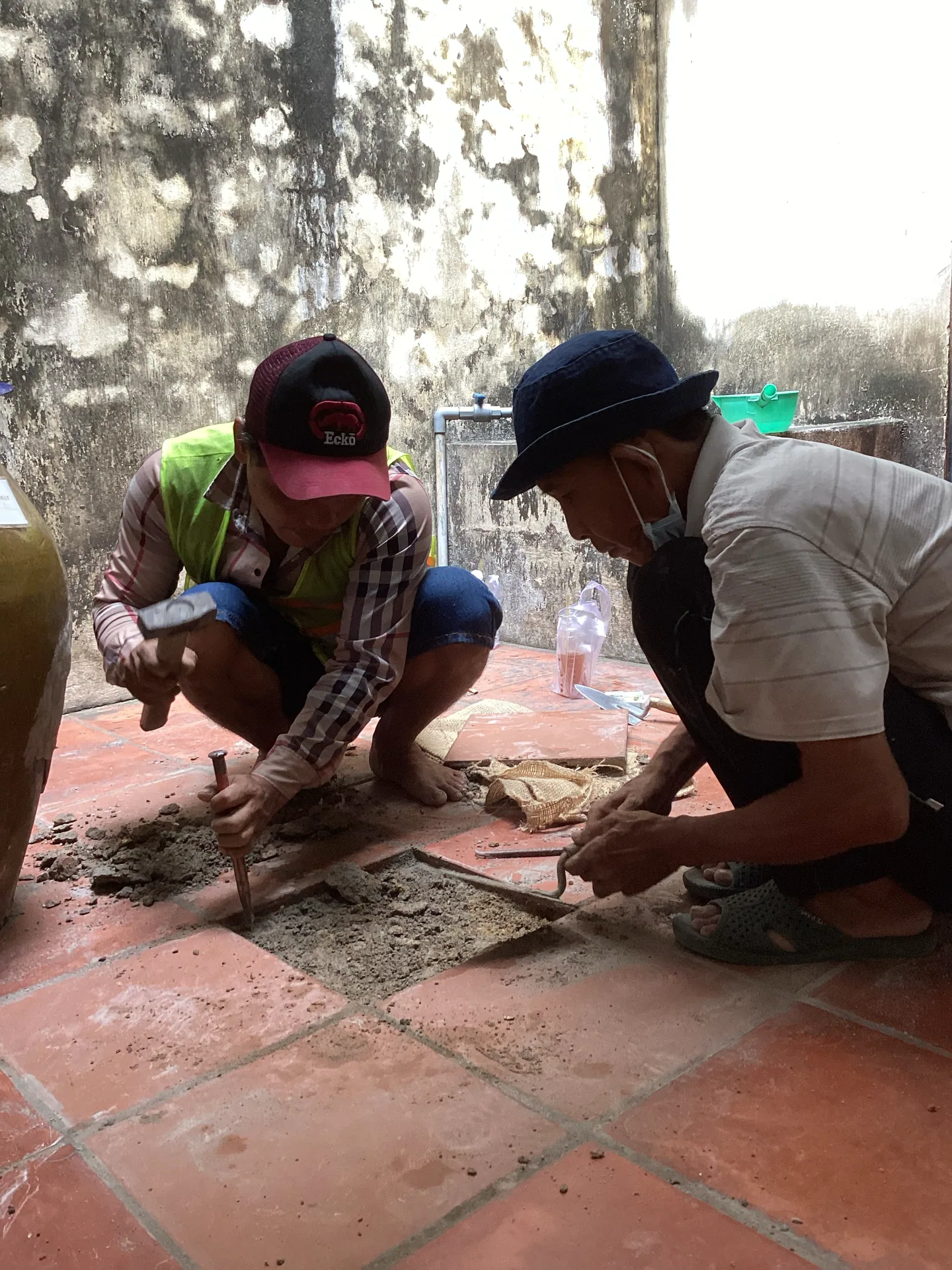 Nhóm người đang xử lý, sửa chữa nền gạch trong khu vực di tích.