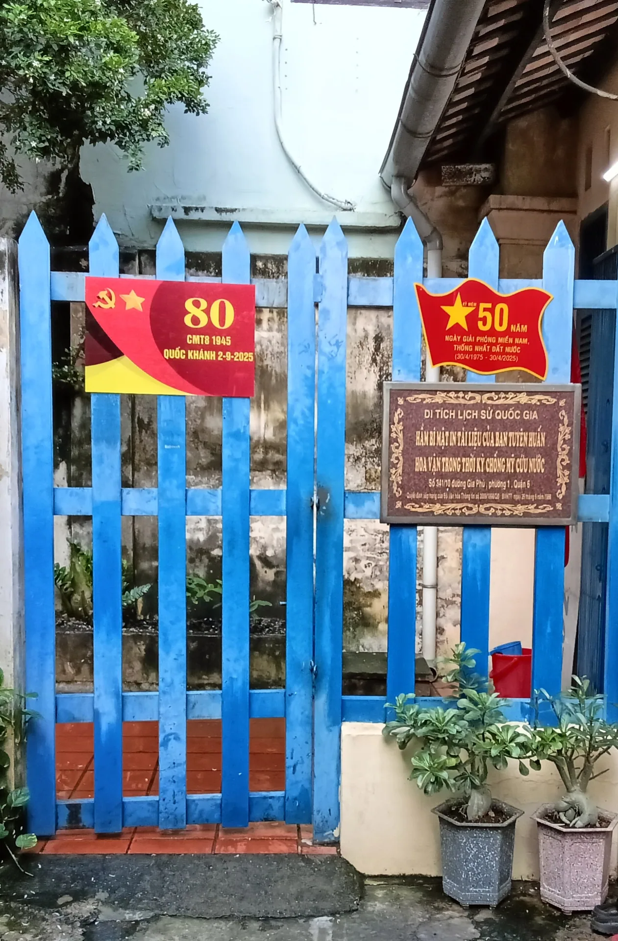 Cổng màu xanh của điểm di tích, có bảng kỷ niệm 80 năm Cách mạng Tháng Tám và Quốc khánh 2-9-2025.