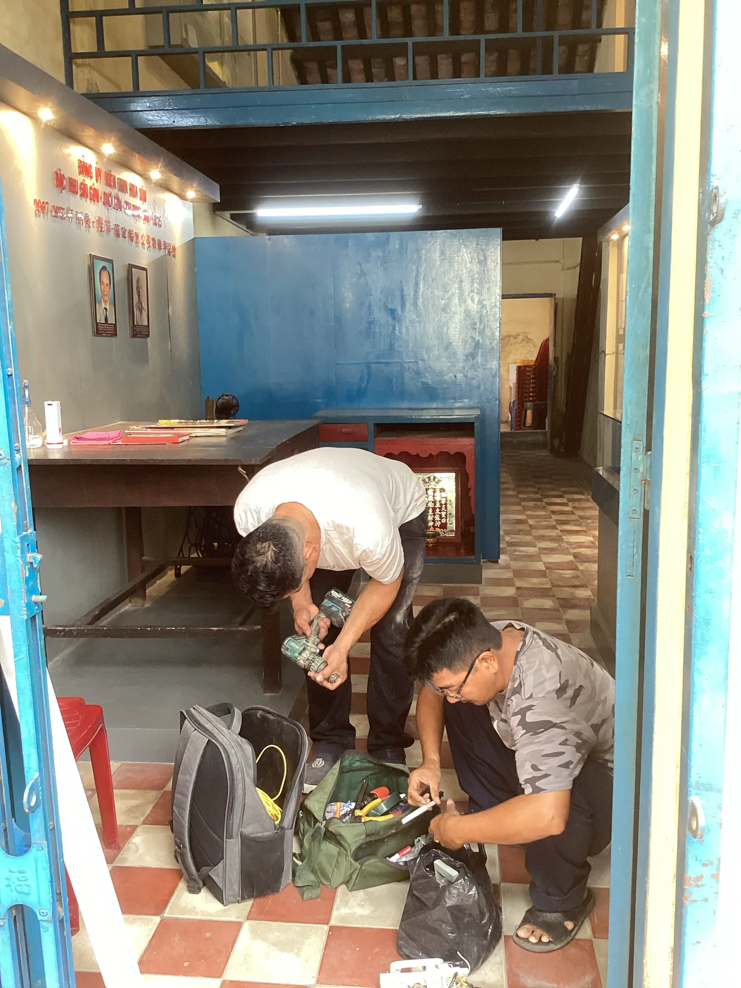 Nhóm người đang làm việc trong phòng trưng bày, quanh một hiện vật hoặc thiết bị dưới sàn.