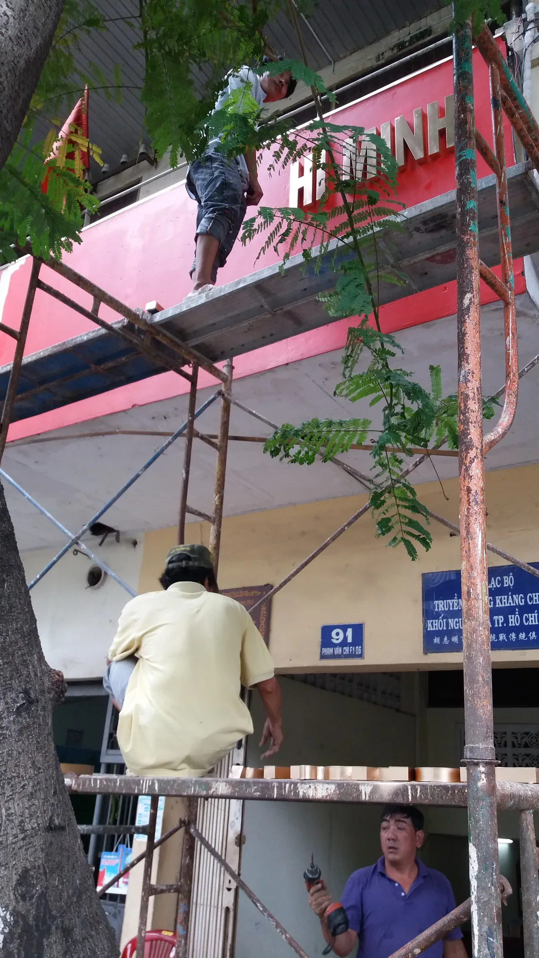 Nhân công đứng trên giàn giáo trước mặt tiền nhà di tích để thi công, sửa chữa.