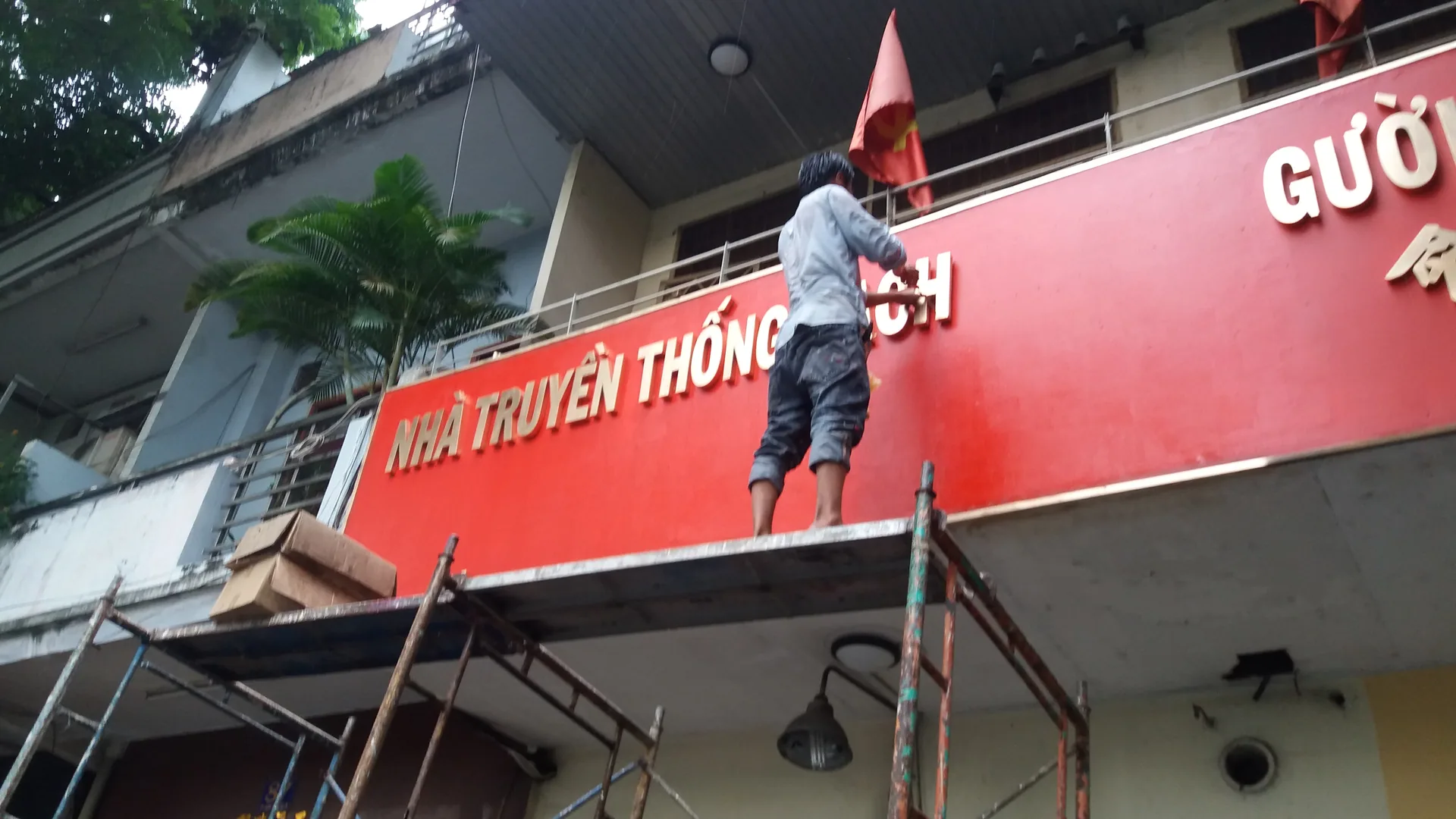 Nhân công trên giàn giáo đang thi công bảng hiệu Nhà Truyền thống Cách mạng Người Hoa TP.HCM.